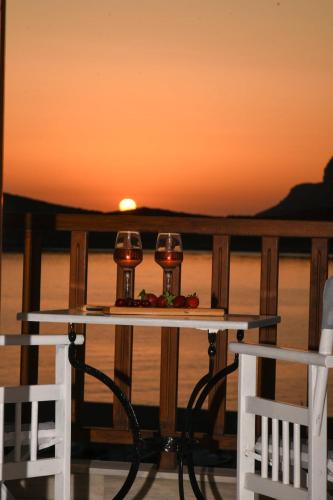 two glasses of wine sitting on a table with the sunset at Australia Apartments in Kalymnos