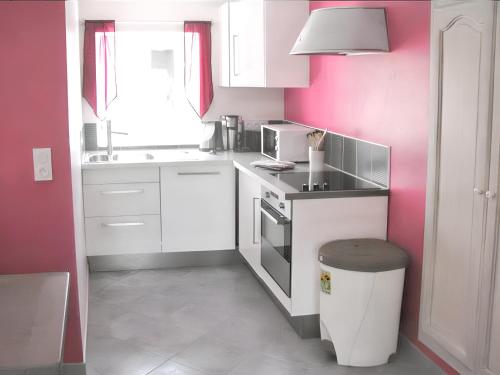 eine Küche mit weißen Schränken und einer rosa Wand in der Unterkunft Appartement d'une chambre avec terrasse amenagee et wifi a Saint Genes du Retz in Saint-Genès-du-Retz