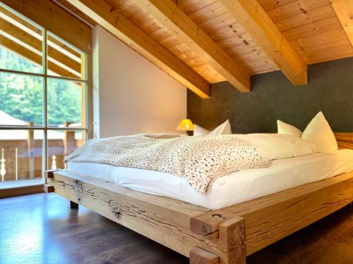 a bedroom with a wooden bed with a large window at Alpenlodge Charivari - SommerBergBahn unlimited kostenlos in Oberstdorf