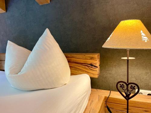 a bedroom with a bed with a pillow and a lamp at Alpenlodge Charivari - SommerBergBahn unlimited kostenlos in Oberstdorf