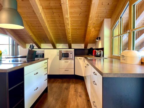 a kitchen with white cabinets and a wooden ceiling at Alpenlodge Charivari - SommerBergBahn unlimited kostenlos in Oberstdorf