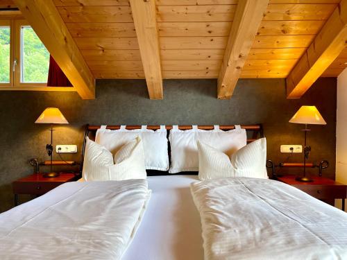 two beds in a bedroom with wooden ceilings at Alpenlodge Charivari - SommerBergBahn unlimited kostenlos in Oberstdorf