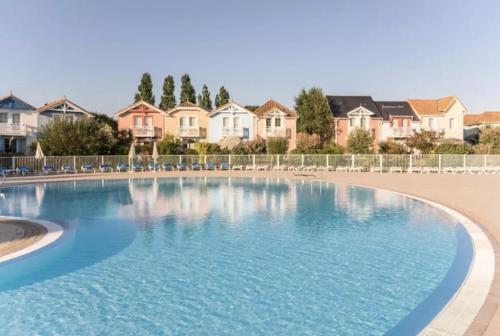 une grande piscine avec des maisons en arrière-plan dans l'établissement Maison 6 personnes - Piscines, Tennis, Golf & Plage, à Talmont-Saint-Hilaire