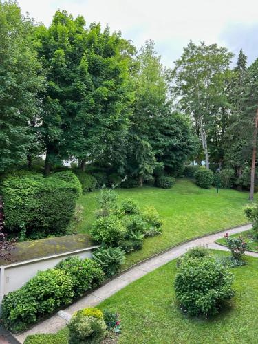 a garden with bushes and trees and a walkway at Chambre indépendante dans résidence calme, proche Paris in Bougival
