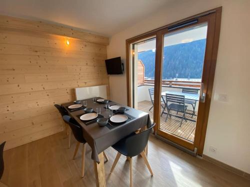 Una habitación con una mesa con sillas y un balcón. en Perle de Savoie A203, en Châtel