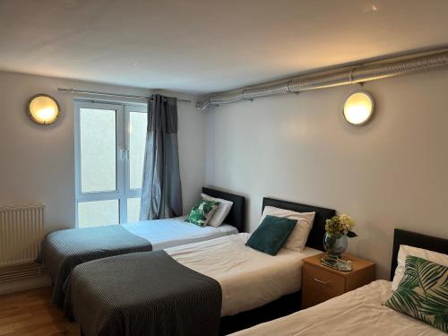 two beds in a room with a window at Access Apartments City in London