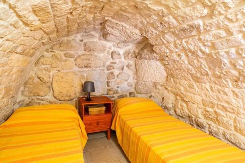 two beds in a room with a stone wall at Casa Vacanze Cattedrale in Ostuni