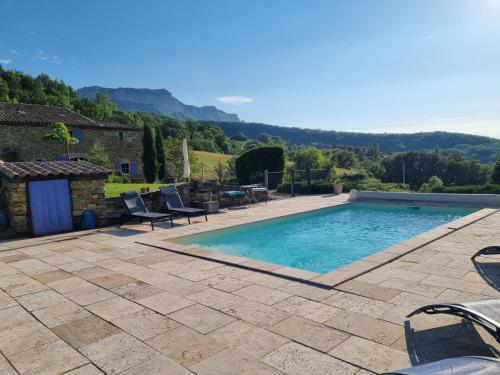 une piscine avec un patio et des montagnes en arrière-plan dans l'établissement Chambres d'hôtes Le St Maurice, à Truinas