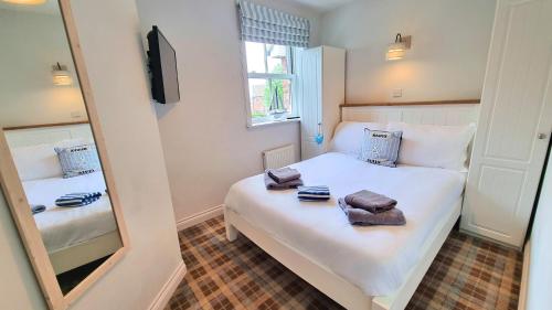 een kleine slaapkamer met 2 bedden en een spiegel bij The Bay Filey - Corner Cottage - Perfect Location - Refurbished 2024 in Filey