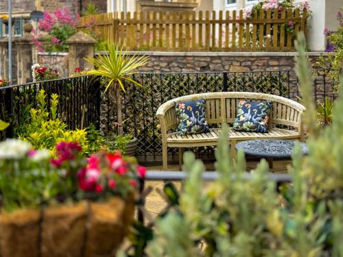 two benches with pillows in a garden with flowers at Timbertop Suites - Adults Only in Weston-super-Mare