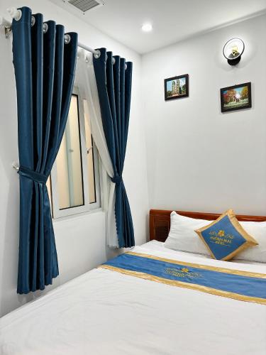 a bedroom with a bed and a window with blue curtains at Huong Mai Hotel in Da Lat