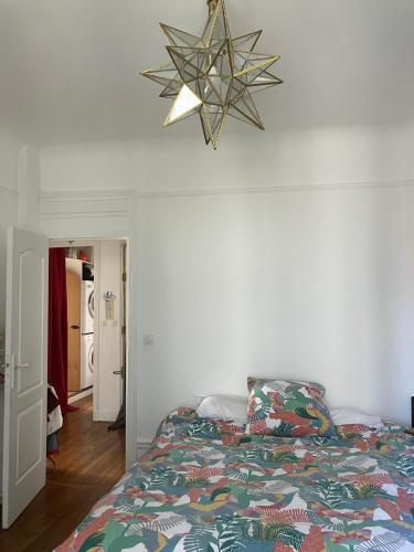a bedroom with a bed and a chandelier at Appartement chateau de Vincennes JEUX OLYMPIQUES in Vincennes