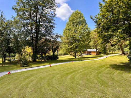 a grassy field with trees and a road at Manoir Nestor - Chairière in Vresse-sur-Semois