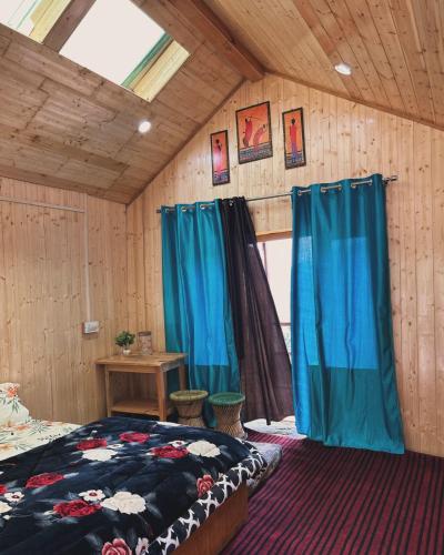 a bedroom with blue curtains and a bed in a room at Parashar lake Fogg hill Resort in Prashar lake