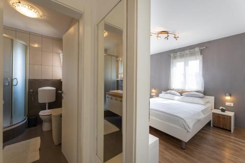 a bedroom with a bed and a bathroom with a mirror at Apartments Belmat in Trogir