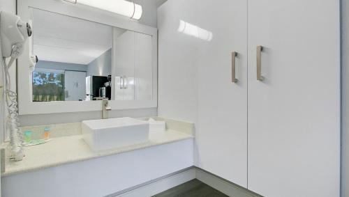 a white bathroom with a sink and a mirror at Home 1 Suites Extended Stay - Kissimmee in Kissimmee