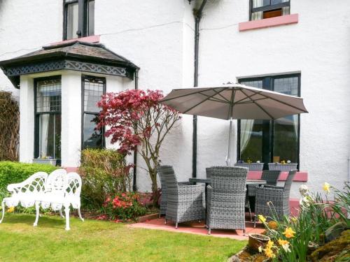 a patio with a table and chairs and an umbrella at Tigh N Eilean Self Catering Aberfeldy in Aberfeldy