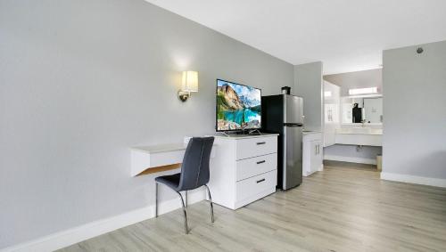 a room with a desk and a refrigerator and a chair at Home 1 Suites Extended Stay - Kissimmee in Kissimmee