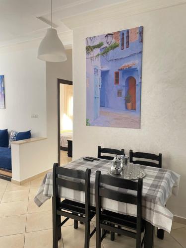 a dining room table with two chairs and a painting at Azur by Azur spacieux, emplacement idéal et proche de la plage in Oued Laou