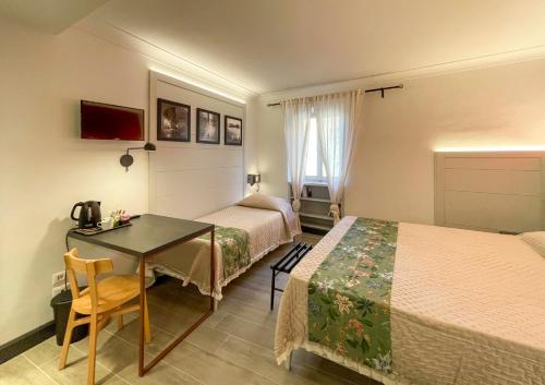 a hotel room with two beds and a table at Duccio Nacci Rooms- Guesthouse in San Gimignano
