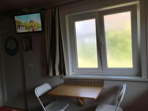 a table and two chairs in a room with a window at Le petit Nid a Coxyde in Koksijde