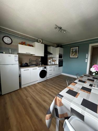 une cuisine avec des armoires blanches et une table dans une pièce dans l'établissement Gite 