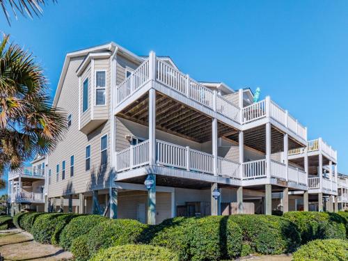 a large white building with balconies and bushes at SEArenity in Surf City