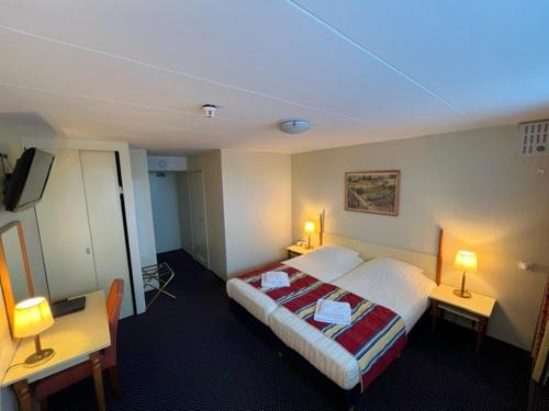 a hotel room with a bed and two tables and two lamps at Boulevard Hotel Scheveningen in Scheveningen
