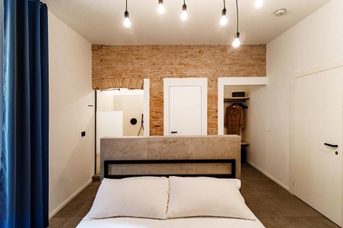 a bedroom with a bed and a brick wall at Guesthouse Linaio - The House Of Travelers in Como