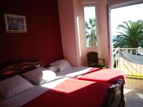 a bedroom with two beds and a large window at Hôtel Azur in Nice