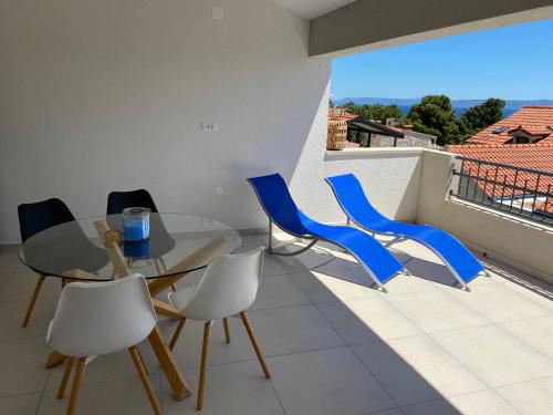 a dining room with a glass table and blue chairs at Penthouse Vanja in Bol