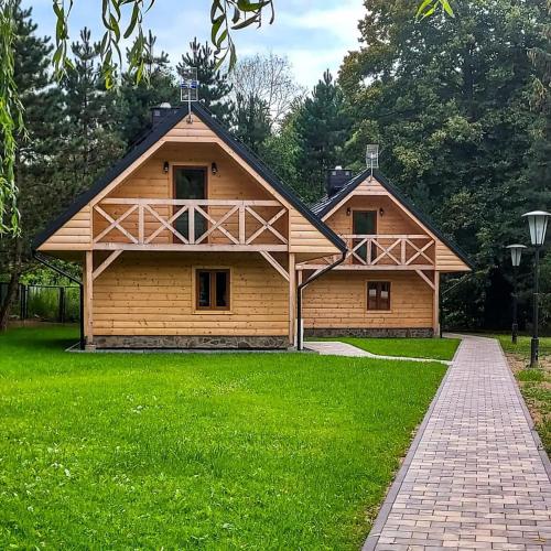 a large wooden house in a field of green grass at Siedlisko nad Białką in Głuchołazy
