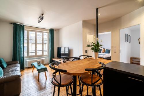 un salon avec une table et des chaises en bois dans l'établissement Mon Appart'hôtel - Gare de Limoges - Appartement familial - Parking en supp, à Limoges