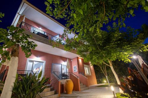 a red and white building with a balcony at night at Aurora Premium Hospitality in Parga