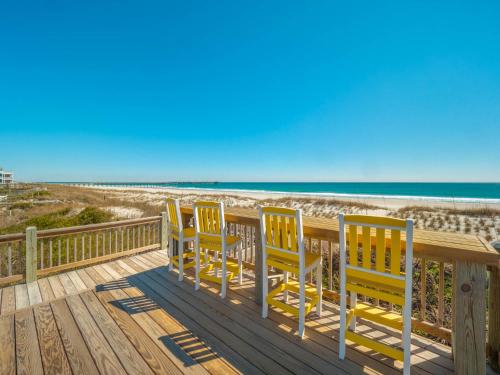 a row of yellow chairs on a deck at the beach at Serendipity in Surf City