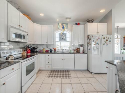 a kitchen with white cabinets and a white refrigerator at Serendipity in Surf City