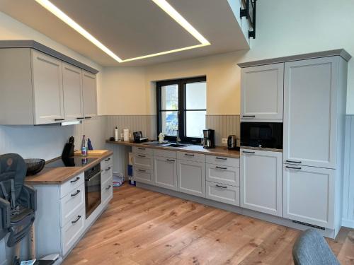 a large kitchen with white cabinets and wooden floors at Ferienhaus Inselglück in der Puddeminer Wiek in Poseritz