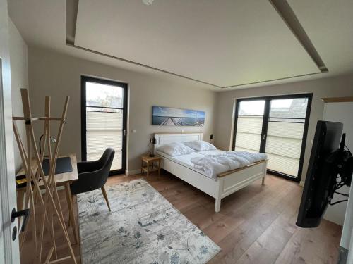 a bedroom with a bed and a desk and windows at Ferienhaus Inselglück in der Puddeminer Wiek in Poseritz