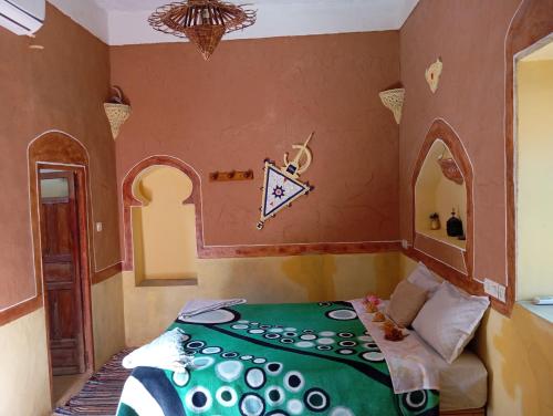 a bedroom with a bed with a green comforter at Kasbah tifaoute ait Ben haddou in Aït Ben Haddou