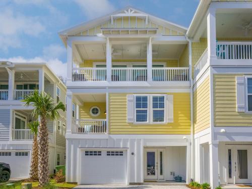 a yellow and white house with a palm tree in front at Serenity By the Sea in Kure Beach