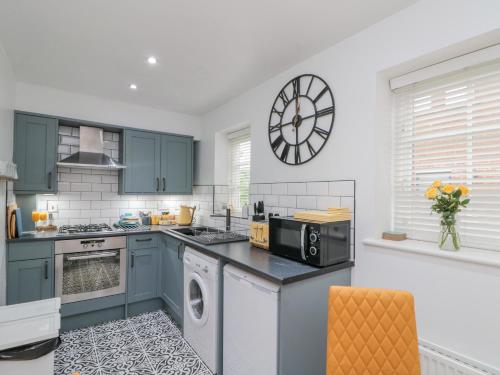 a kitchen with blue cabinets and a clock on the wall at Little Nest Cottage in Guisborough