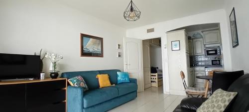 un salon avec un canapé bleu et une télévision dans l'établissement Studio terrasse face à la plage JUAN LES PINS, à Antibes