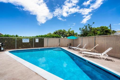 a swimming pool with two chairs and a fence at Kailua Village#201 in Kailua-Kona