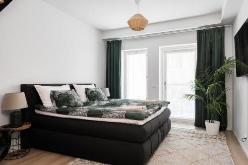 a bedroom with a black bed with green curtains at Loft Itäpuisto By Borg Housing in Pori