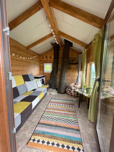 a bedroom in a log cabin with a bed and a rug at Langaland Glamping in Susenii Bîrgăului