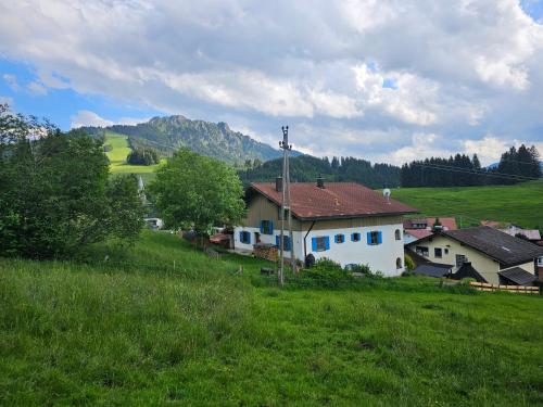 a white house on a hill with a green field at Jungholz Erlebnis in Jungholz