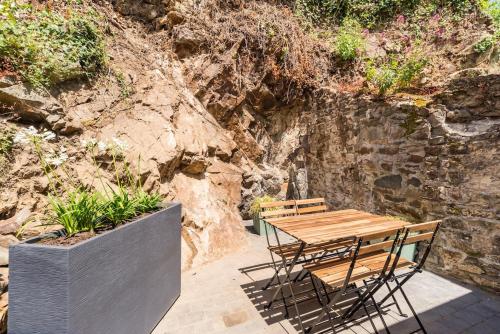 a wooden table and chairs next to a stone wall at Charmante maison neuve avec terrasse Port du Legue in Plérin