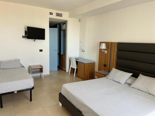 a bedroom with two beds and a desk with a television at Almare' B&b in Torre Santa Sabina