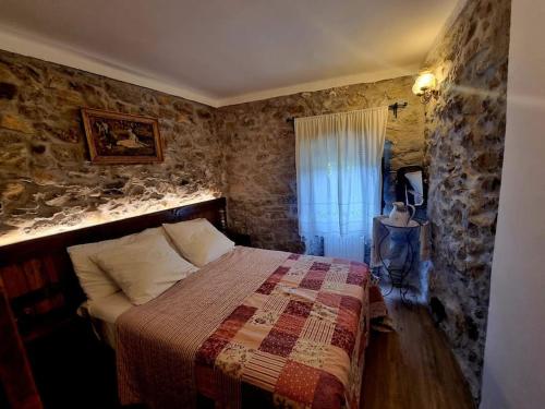 a bedroom with a bed and a stone wall at Can Catalina in Terrades