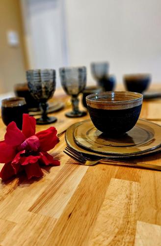 une table en bois avec un bol et une fleur rouge dessus dans l'établissement La petite maison bleue, à Mouret